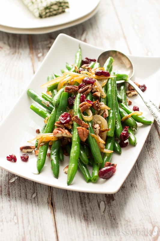 This easy side dish is perfect for Thanksgiving. Crisp green beans get tossed with caramelized onions, toasted pecans, and dried cranberries. | www.themessybakerblog.com