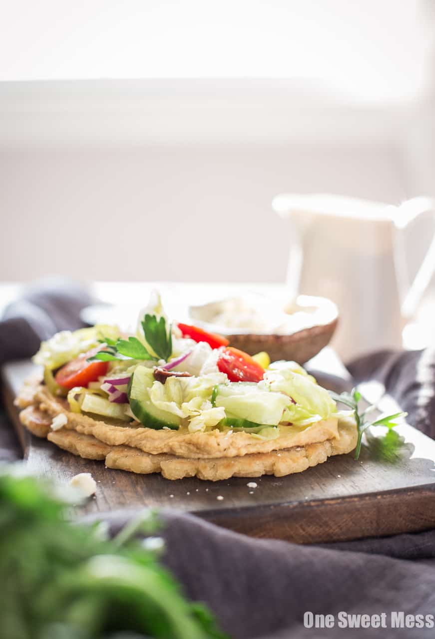 Gluten-Free Greek Salad Naan Pizza: Gluten-Free Naan smeared with creamy hummus and topped with a mound of fresh Greek salad.